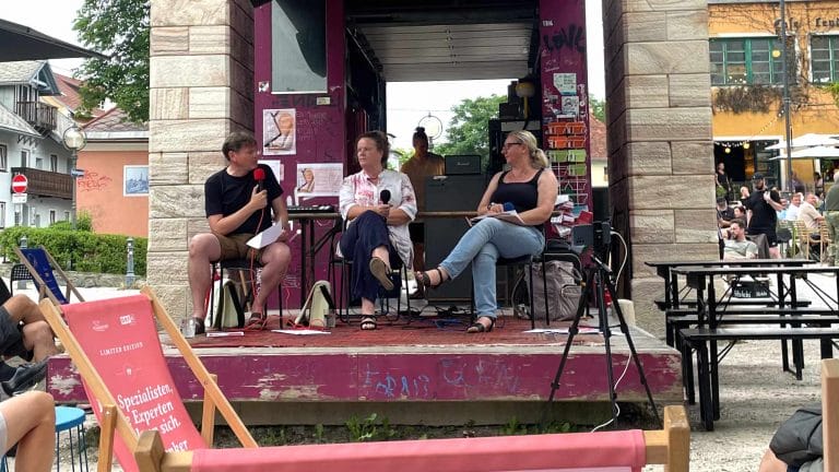 Die beiden Podcaster Wolfgang Tischer (links) und Bozena Badura (rechts) sprechen mit ihrem Gast Doris Moser (Mitte) auf der Bühne am Lendhafen über den dritten Lesetag in Klagenfurt